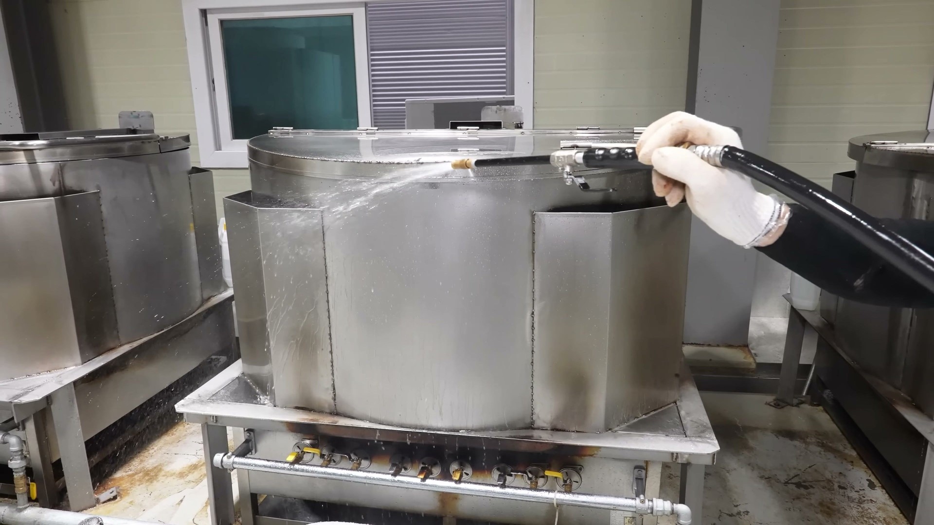 High pressure water hose cleaning an industrial gastronomic pan
